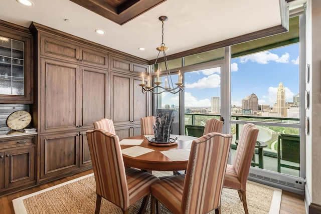dining room featuring recessed lighting, a city view, a chandelier, and wood finished floors