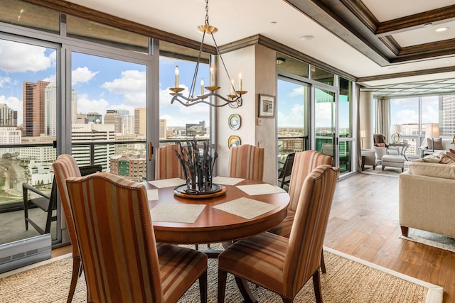 dining area featuring floor to ceiling windows, an inviting chandelier, crown molding, a view of city, and light wood-style floors