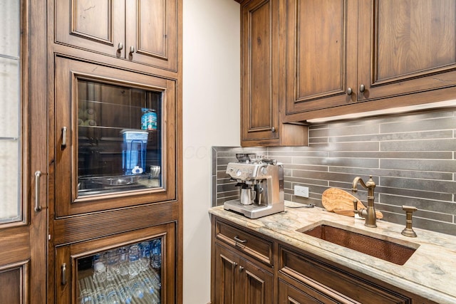 kitchen featuring a sink, decorative backsplash, and light stone countertops