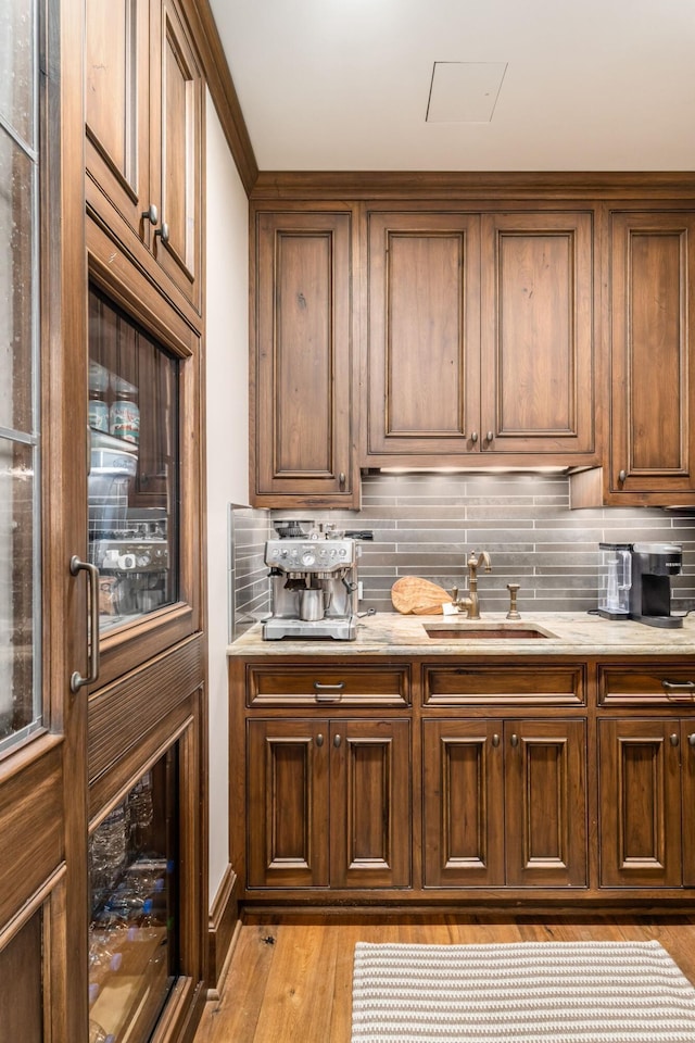 kitchen featuring a sink, decorative backsplash, and light wood-style floors