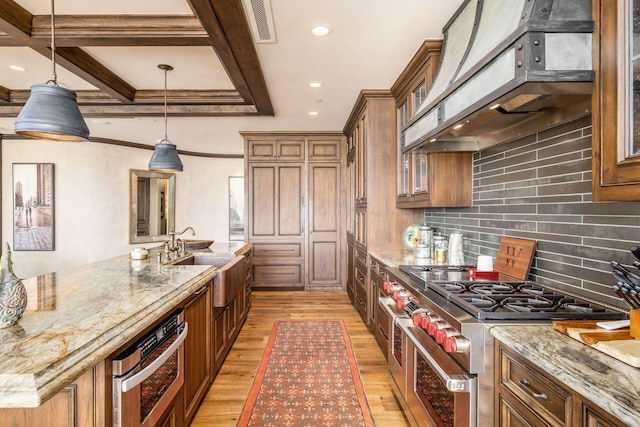 kitchen with decorative backsplash, double oven range, visible vents, brown cabinets, and ventilation hood