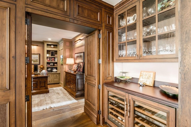 bar featuring crown molding, wood finished floors, and built in shelves