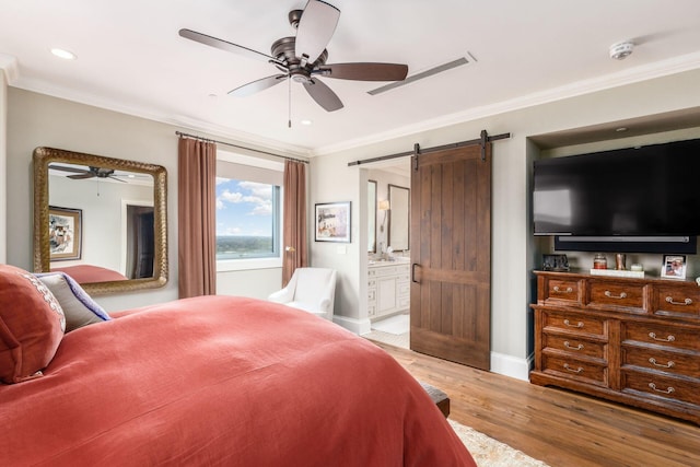 bedroom featuring crown molding, a barn door, baseboards, light wood-style floors, and ensuite bathroom