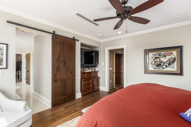 bedroom featuring crown molding, wood finished floors, a barn door, and visible vents