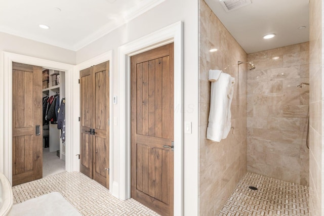 bathroom featuring a walk in closet, visible vents, crown molding, a tile shower, and recessed lighting
