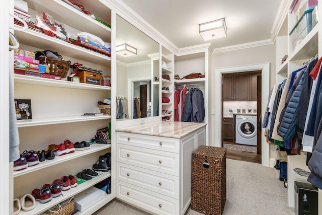 walk in closet with washer / clothes dryer and light colored carpet