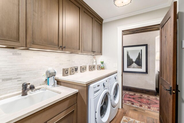 1 Miranova Pl Unit 2230, Columbus, OH 43215 - laundry room featuring ornamental molding, wood finished floors, washing machine and clothes dryer, a sink, and cabinet space