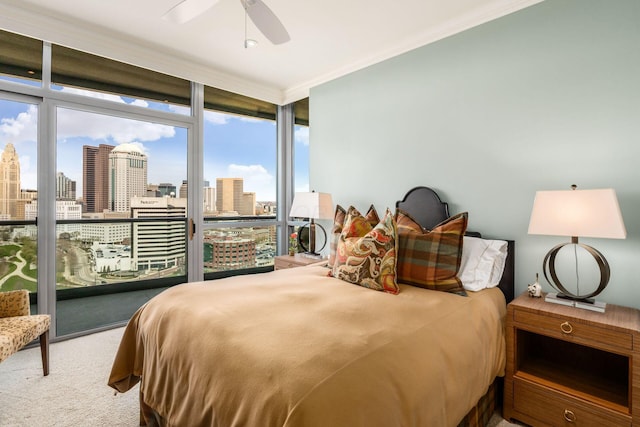 bedroom with floor to ceiling windows, access to outside, a city view, ornamental molding, and carpet flooring