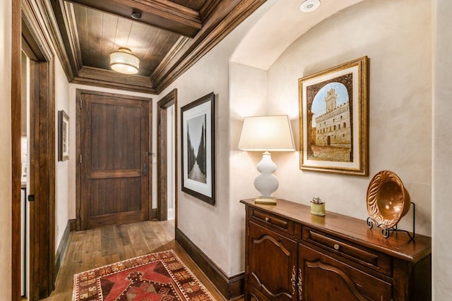 hall featuring crown molding, dark wood-style flooring, baseboards, and wooden ceiling