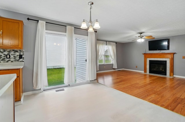 7622 Elgin Trail Dr, Blacklick, OH 43004 - unfurnished living room with baseboards, visible vents, ceiling fan with notable chandelier, a fireplace, and light wood-type flooring