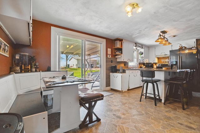 kitchen with stone flooring, open shelves, a breakfast bar, dark countertops, and white cabinets