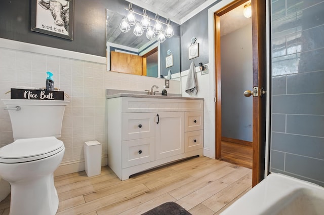 bathroom featuring vanity, wood finished floors, toilet, and tile walls
