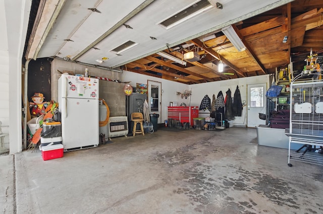 garage featuring freestanding refrigerator, heating unit, and a garage door opener