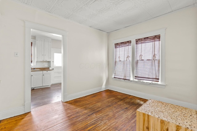 spare room featuring hardwood / wood-style flooring, baseboards, and an ornate ceiling