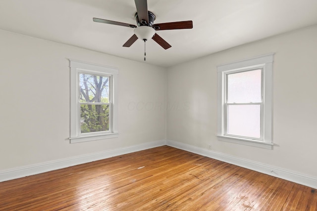 empty room featuring light wood finished floors, baseboards, and a ceiling fan