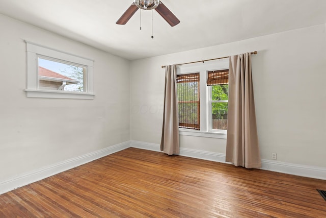 empty room featuring baseboards, visible vents, a ceiling fan, and wood finished floors