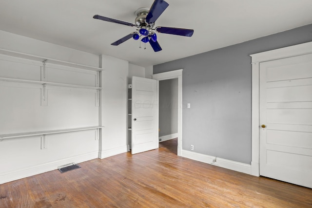 unfurnished bedroom featuring baseboards, a ceiling fan, visible vents, and wood finished floors