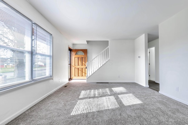311 Williamsburg Ln NW, Lancaster, OH 43130 - unfurnished living room with stairs, baseboards, and carpet