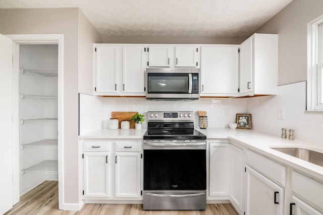 3141 Amberfield Dr, Columbus, OH 43232 - kitchen with light countertops, white cabinetry, appliances with stainless steel finishes, and light wood-style floors