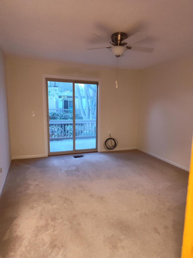 carpeted empty room with baseboards, ceiling fan, and visible vents