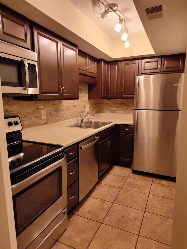 kitchen with appliances with stainless steel finishes, a sink, light countertops, decorative backsplash, and visible vents
