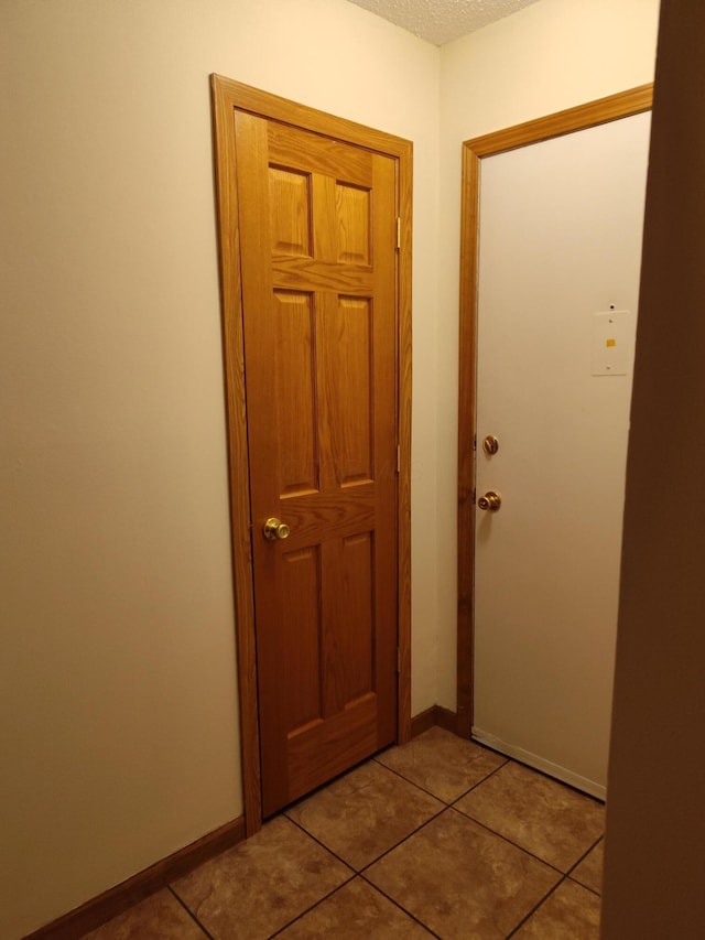 entryway with a textured ceiling, tile patterned floors, and baseboards