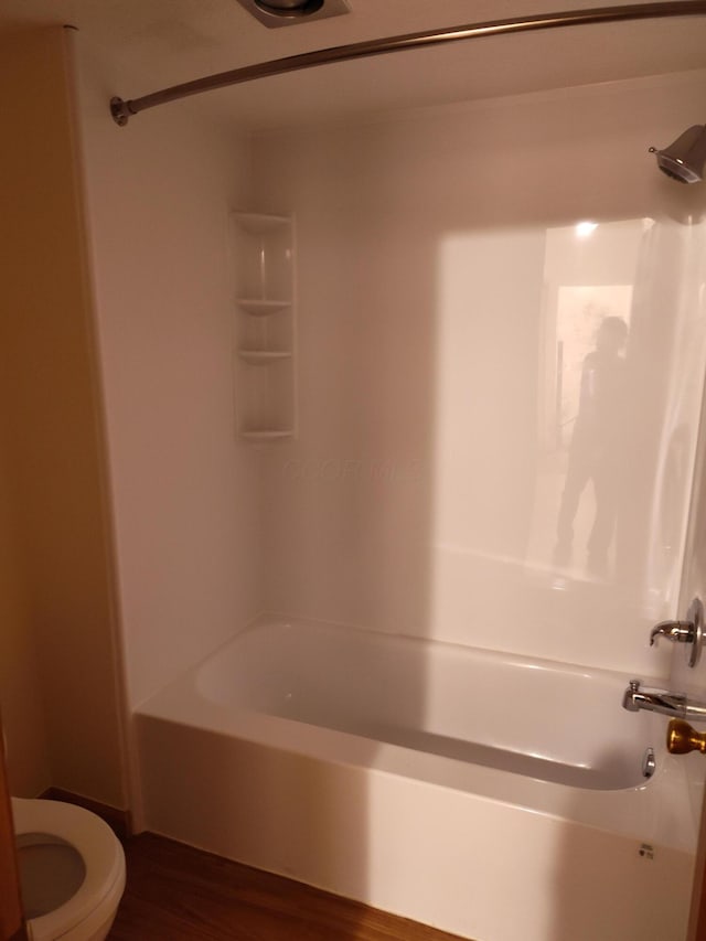 bathroom featuring bathtub / shower combination, toilet, and wood finished floors