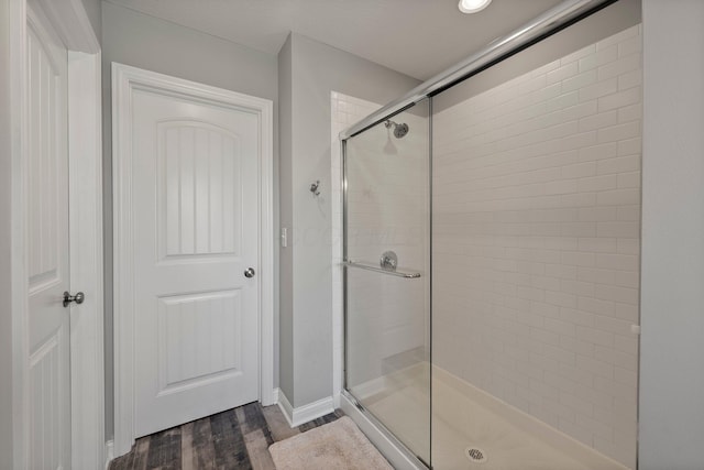full bath featuring baseboards, a stall shower, and wood finished floors
