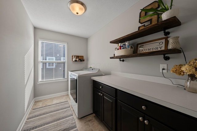 clothes washing area featuring independent washer and dryer, baseboards, and cabinet space