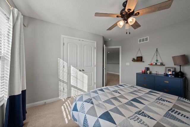 bedroom with light colored carpet, a ceiling fan, baseboards, visible vents, and a closet