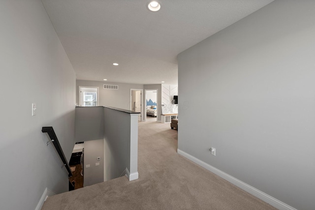 hall with light carpet, recessed lighting, baseboards, an upstairs landing, and visible vents