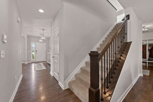 stairs featuring baseboards, wood-type flooring, and a chandelier