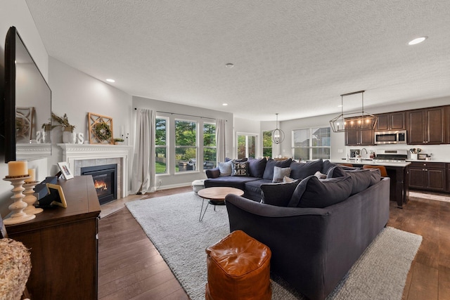 living area with dark wood-type flooring, a textured ceiling, plenty of natural light, and a fireplace