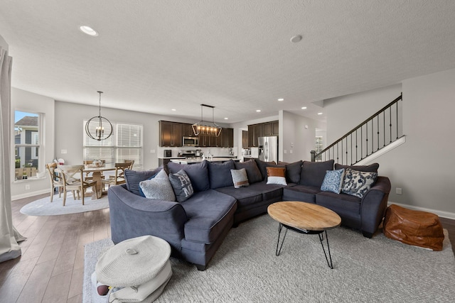living area featuring recessed lighting, light wood-type flooring, a textured ceiling, and a notable chandelier
