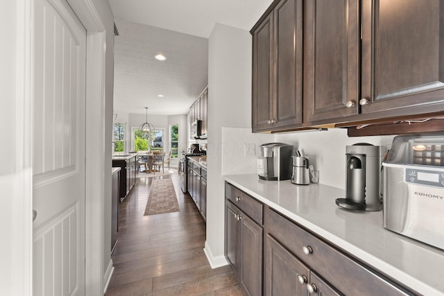kitchen featuring light countertops, backsplash, dark brown cabinetry, and dark wood-style floors
