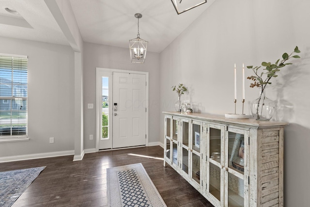 entrance foyer featuring baseboards, a chandelier, vaulted ceiling, and hardwood / wood-style flooring