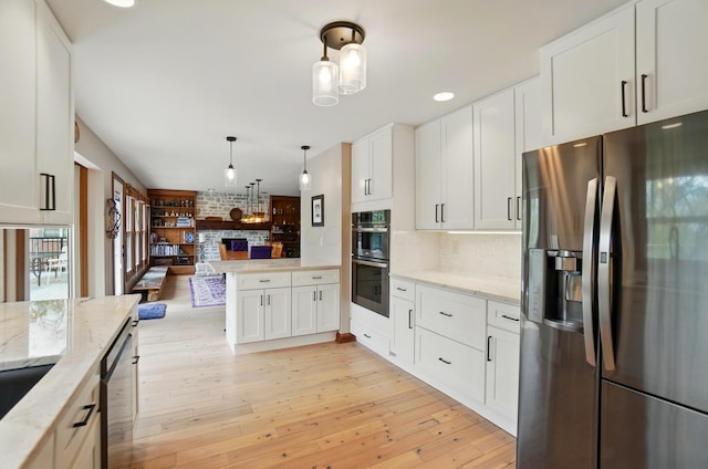9127 Red Cedar Dr, West Chester, OH 45069 - kitchen featuring white cabinets, stainless steel appliances, light wood-type flooring, and a stone fireplace