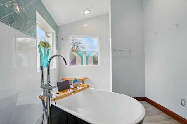9127 Red Cedar Dr, West Chester, OH 45069 - bathroom featuring wood finished floors, baseboards, a freestanding bath, and lofted ceiling