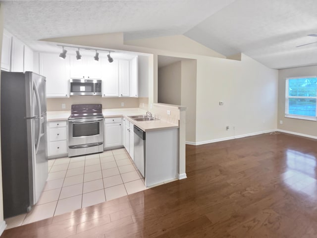 kitchen featuring stainless steel appliances, rail lighting, a sink, and light wood-style floors