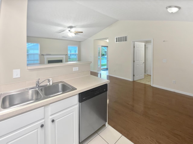 kitchen with a sink, dishwasher, a ceiling fan, vaulted ceiling, and visible vents