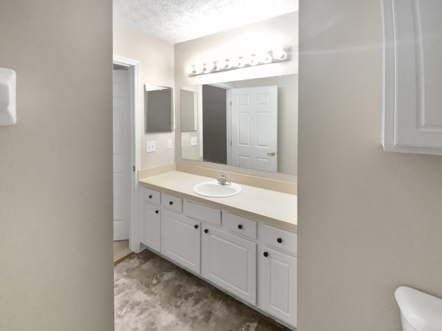 bathroom with toilet, a textured ceiling, and vanity