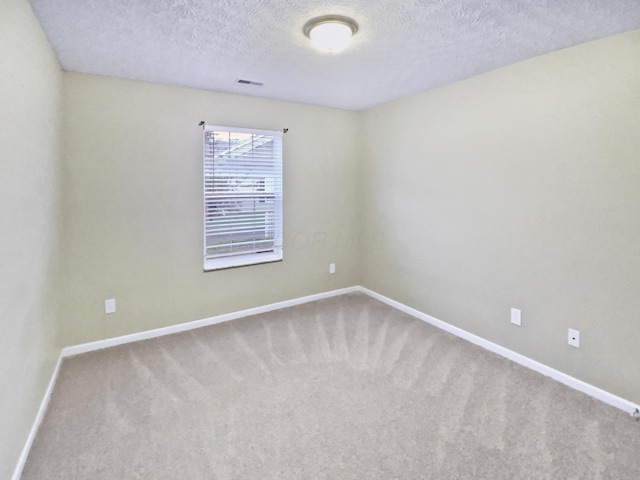 spare room featuring baseboards, carpet floors, a textured ceiling, and visible vents