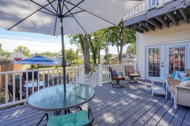 wooden terrace with outdoor dining area, fence, and french doors