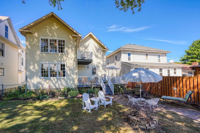 back of property featuring a fenced backyard, a wooden deck, a yard, and an outdoor fire pit