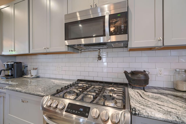 kitchen with light stone counters, backsplash, and stainless steel appliances