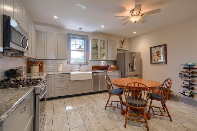 kitchen with gray cabinetry, appliances with stainless steel finishes, decorative backsplash, and a sink