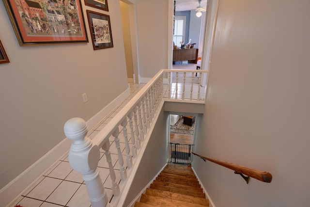 stairway with baseboards and a ceiling fan