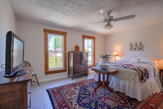 bedroom featuring baseboards, a textured ceiling, ceiling fan, and hardwood / wood-style flooring