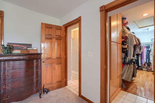 hall featuring attic access and light tile patterned flooring