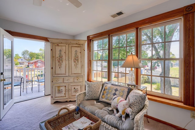 living area featuring visible vents, baseboards, ceiling fan, and light carpet